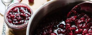 Rote Grütze im Topf und in einem offenen Einmachglas.
