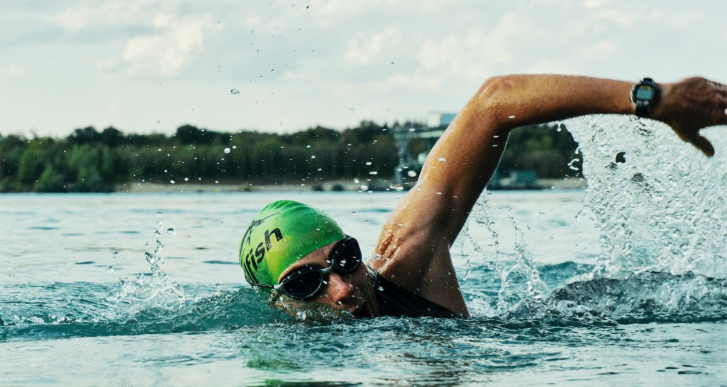 Mann schwimmt im See und macht Kraulbewegungen