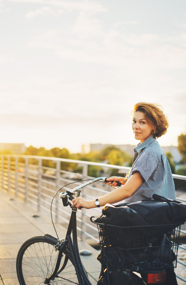 Frau glücklich auf dem Fahrrad, Sonnenuntergang im Hintergrund