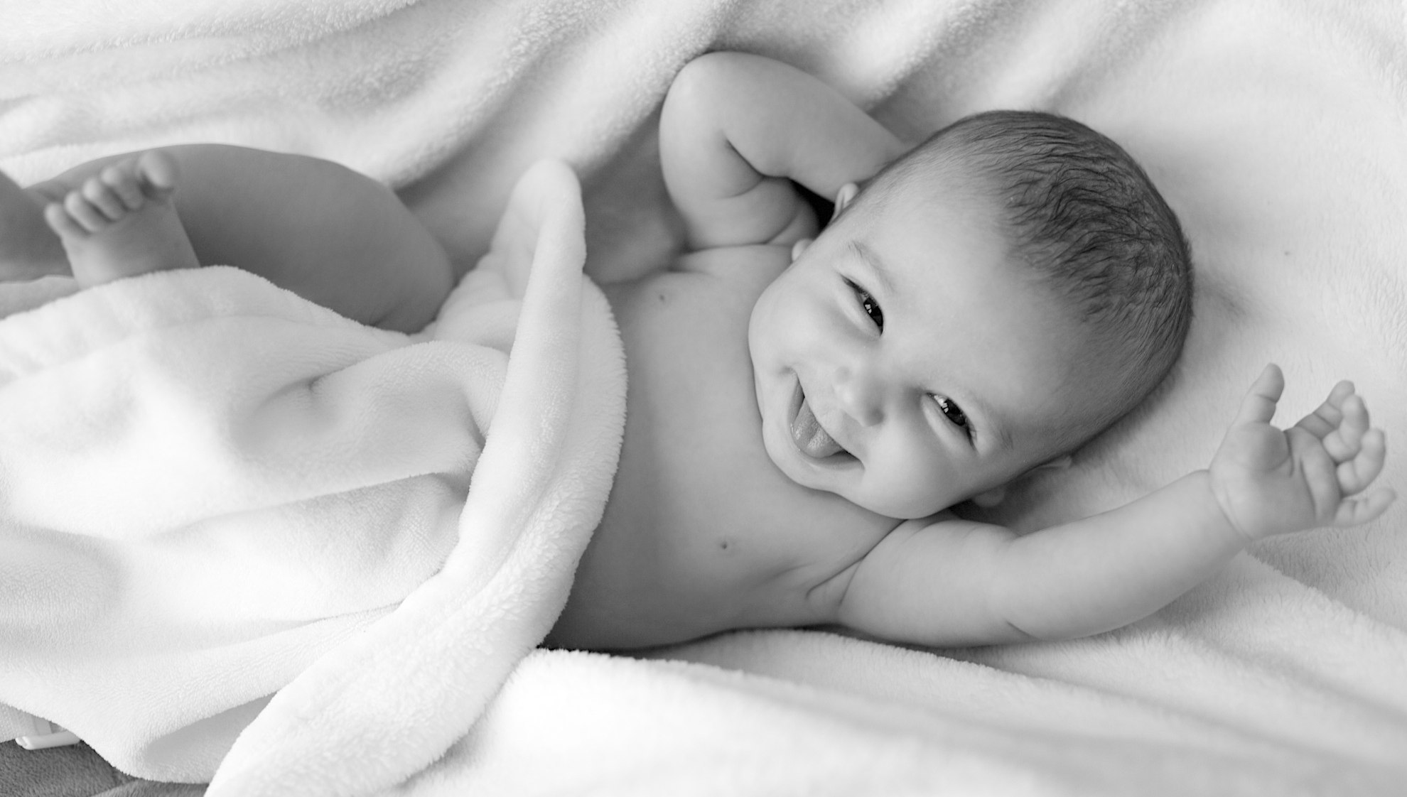 Ein Baby liegt in eine Decke gewickelt auf einem Bett