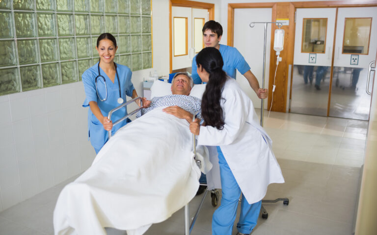 Bild eines Nieren-Lebensspenders, der von motiviertem Pflegepersonal in einem Krankenhausbett in den Operationssaal gefahren wird.