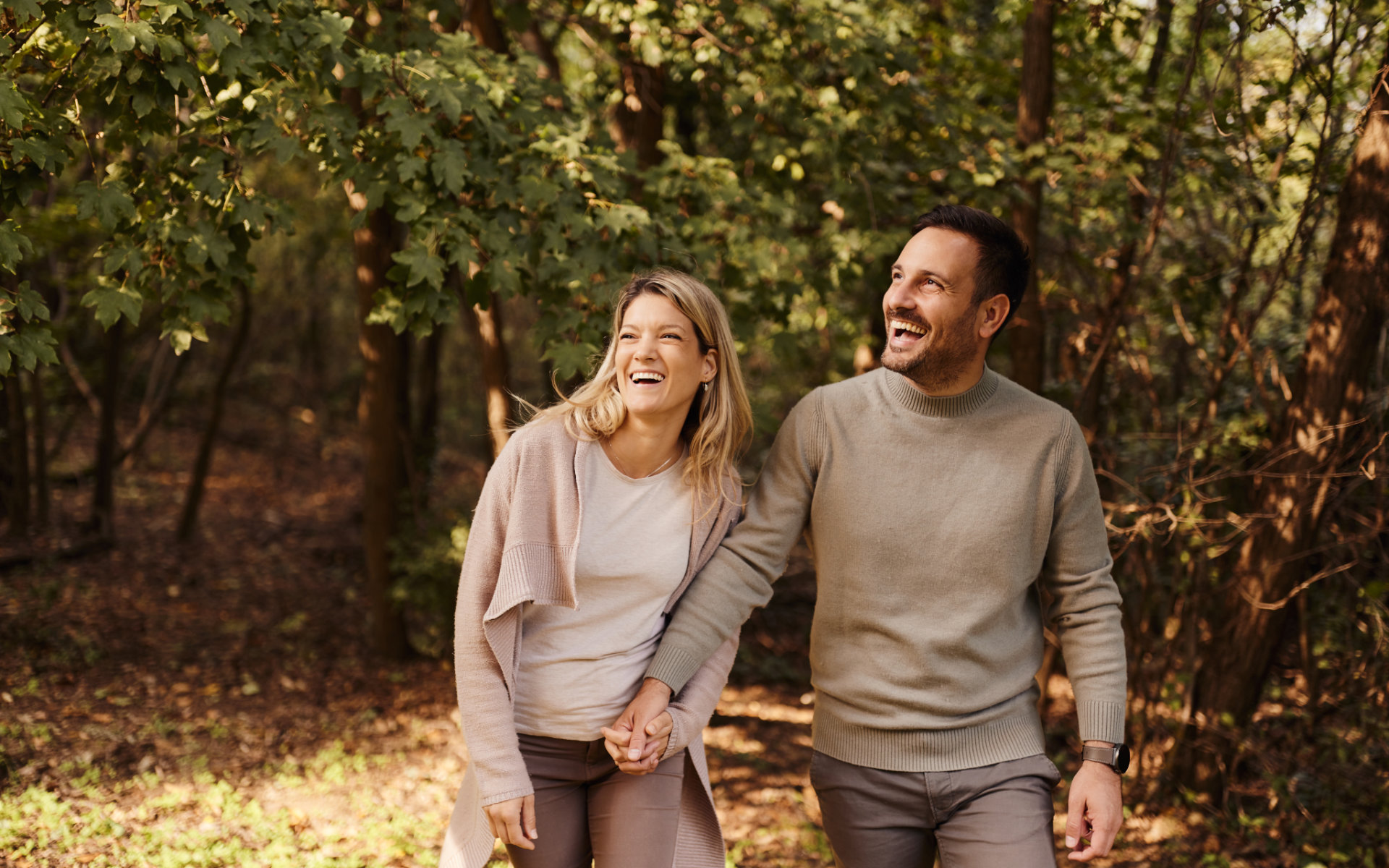 Neuer Alltag nach der Nierentransplantation: eine Frau und ein Mann spazieren glücklich händchenhaltend im Wald