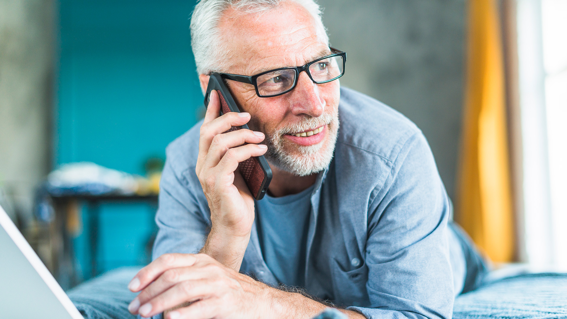Ein älterer Mann mit Brille telefoniert mit seinem Smartphone.